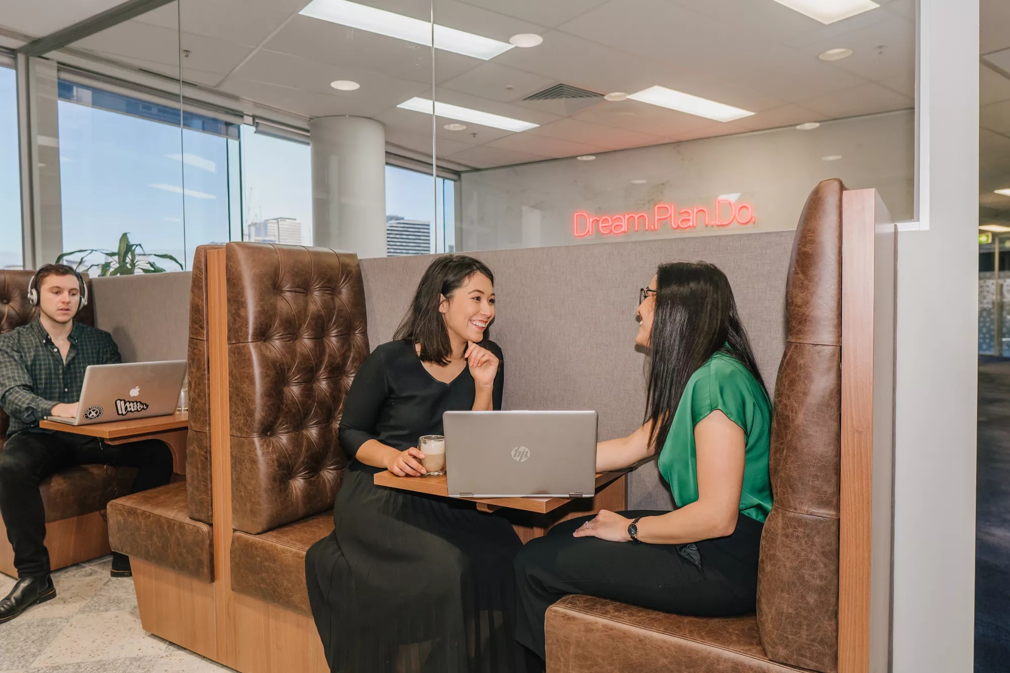 Clients working and conversing in a modern coworking space and booths in Servcorp Southbank, Melbourne
