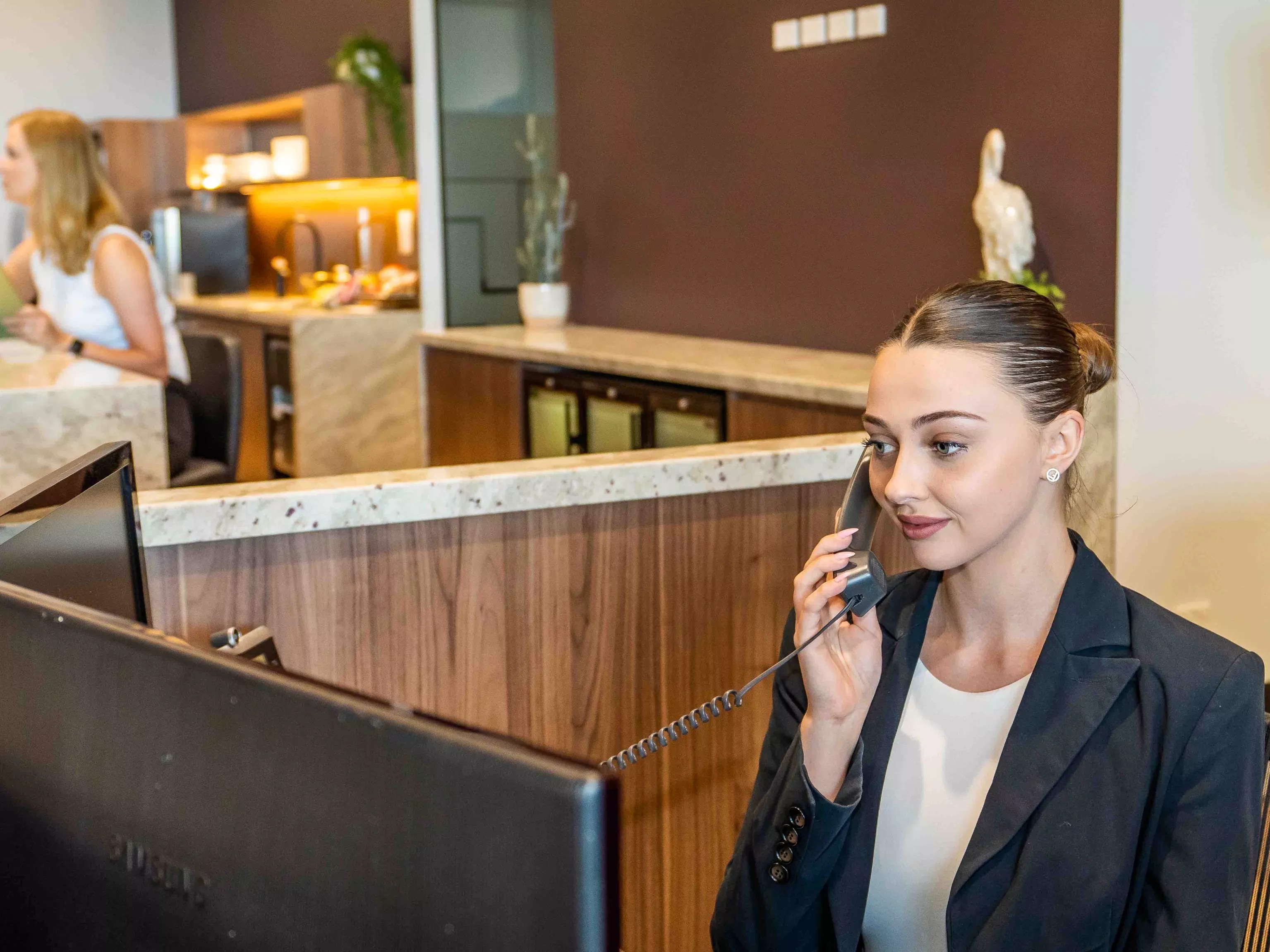 A dedicated receptionist helping a client on the phone in the modern co-working space of in Servcorp 100 Mount Street