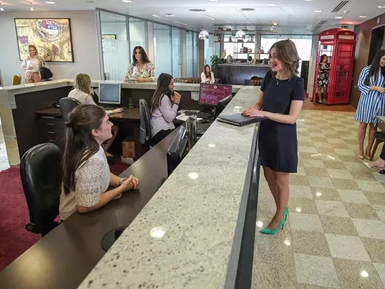 A dedicated receptionist speaking to a client in the modern co-working space of in Servcorp Avaya House, Macquarie Park