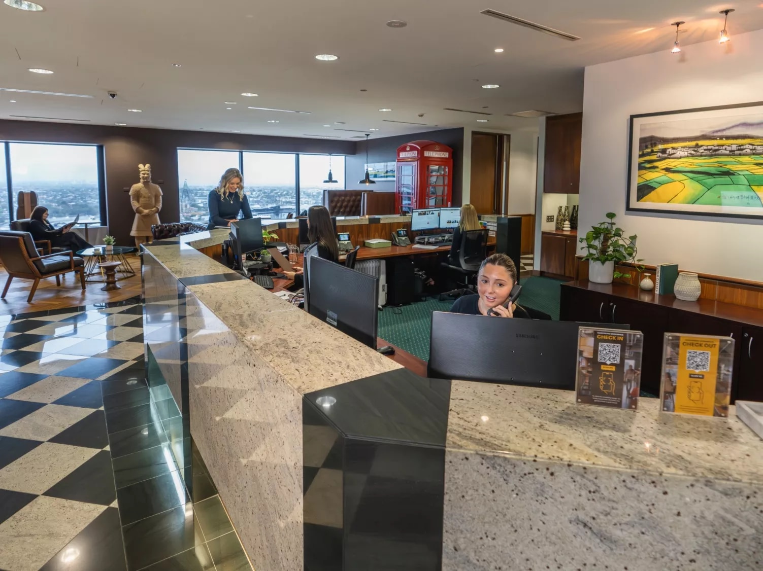 A client talking to the receptionist and another on the phone in a modern coworking space in Servcorp 44 Market Street