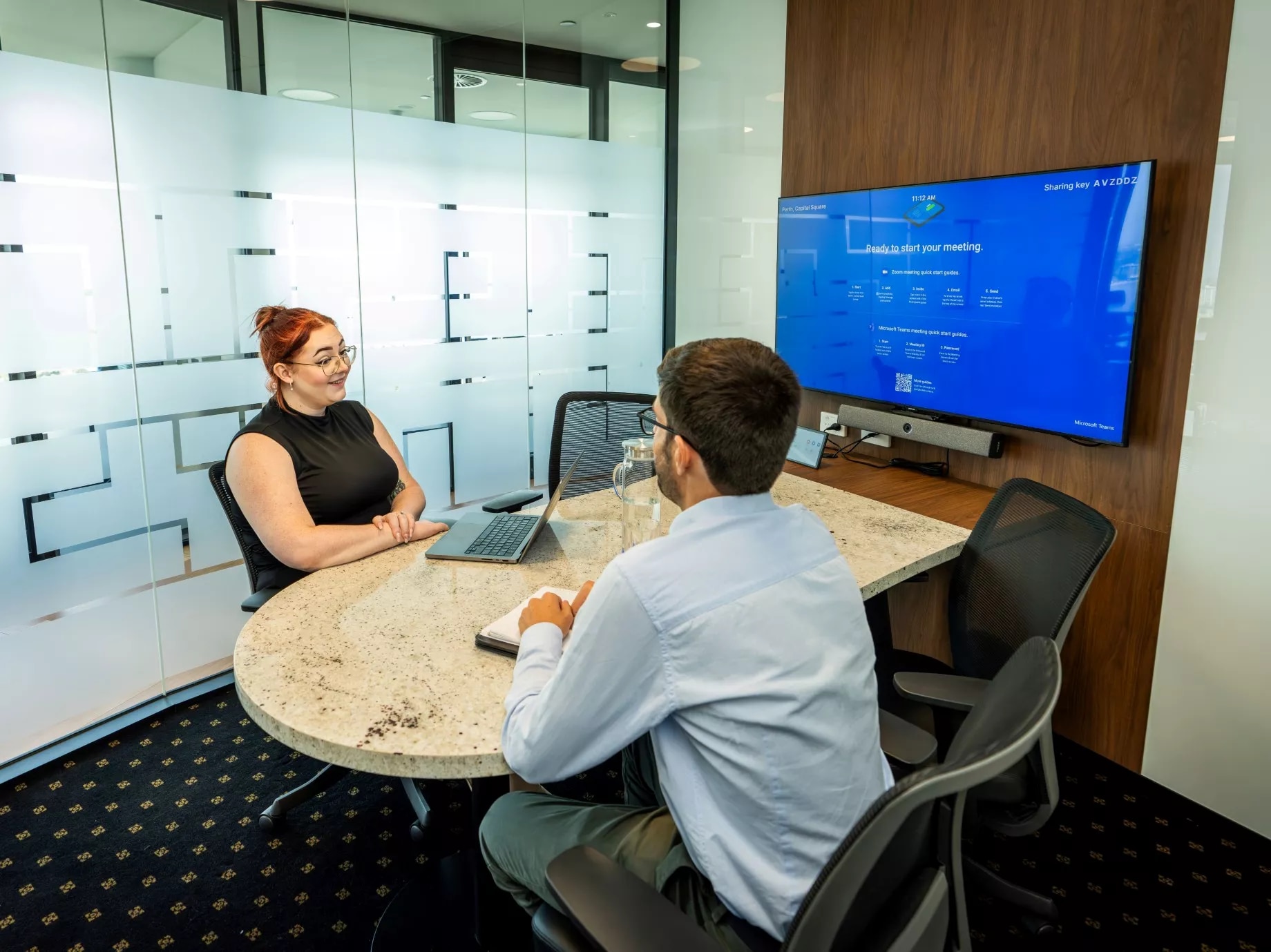 A client talking to her clients in a modern meeting room space using the projection and screen in Servcorp Capital Square Tower 3 Perth
